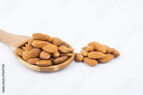 Almonds nuts in wooden ladle isolated on white background. Tasty medicine from nature.