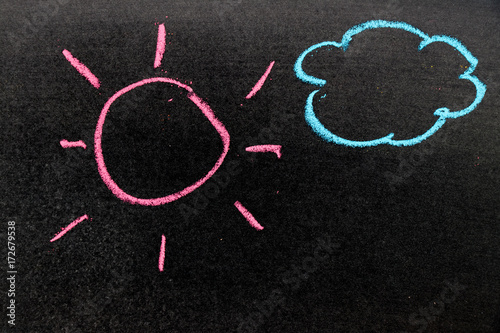 Chalk drawing as pink sun and blue cloud on black board background