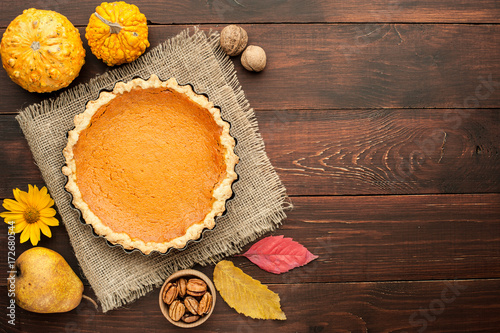 pumpkin homemade pie at wooden background arranged with food ingredients top view