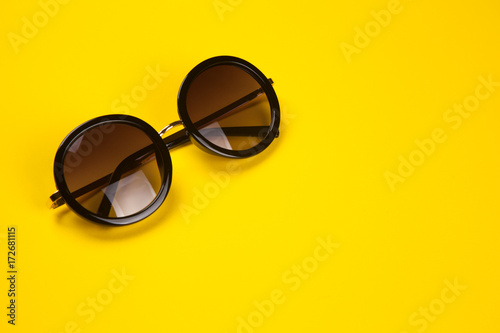 Stylish sunglasses on yellow background