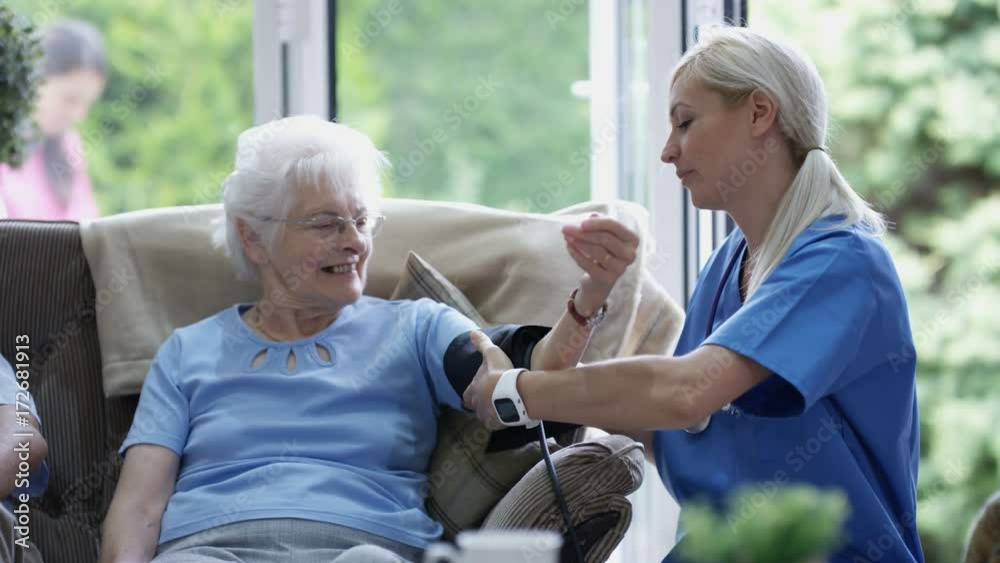 Caring nurse checking elderly lady's blood pressure in nursing home. Caring nurse checking elderly lady's blood pressure in nursing home.