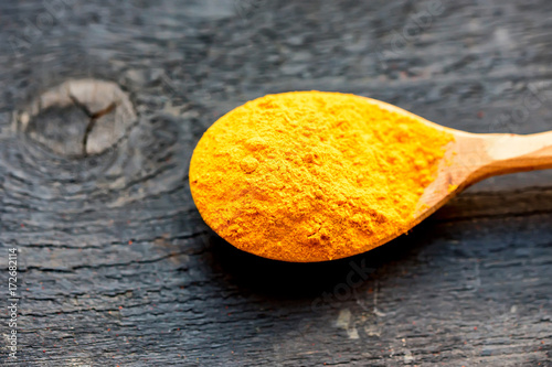 Turmeric powder in wooden spoon close up