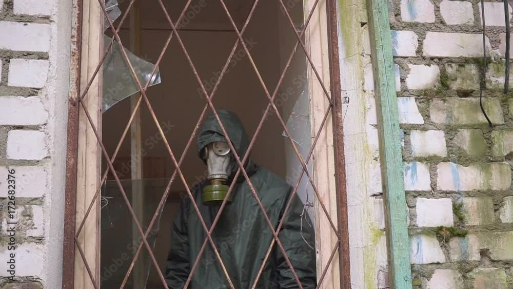 A man with a gas mask looks from window with bars and can not go free A man with a gas mask looks from window with bars and can not go free