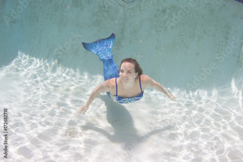 Model in a pool wearing a mermaid's tail.