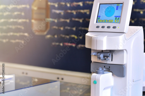 Professional ophthalmology medical instrument in clinic office and optics with glasses in background. Eye health care concept. Selective focus.