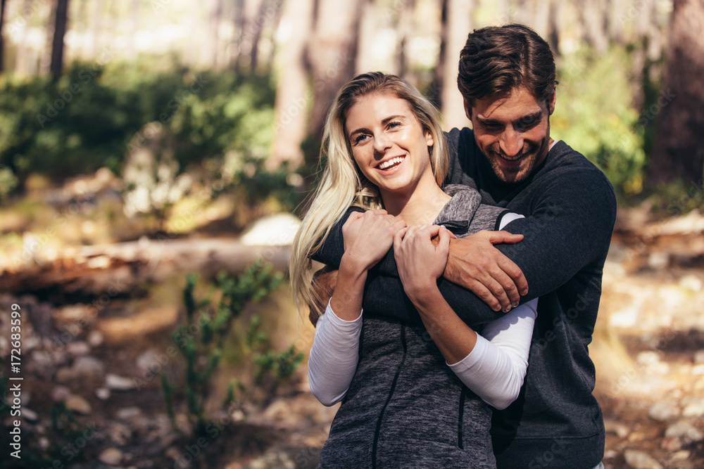 Man holding his woman partner from behind in forest