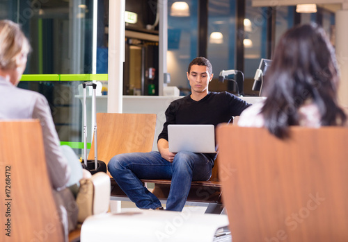 Young Man Using Laptop At Airport Waiting Lobby