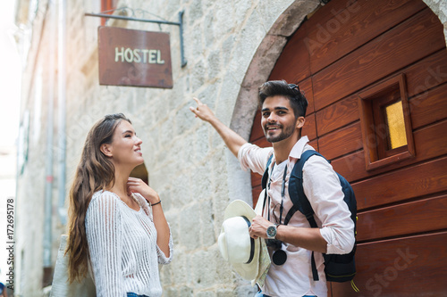 Tourist couple enjoying sightseeing and exploring city pointing a finger at hostel