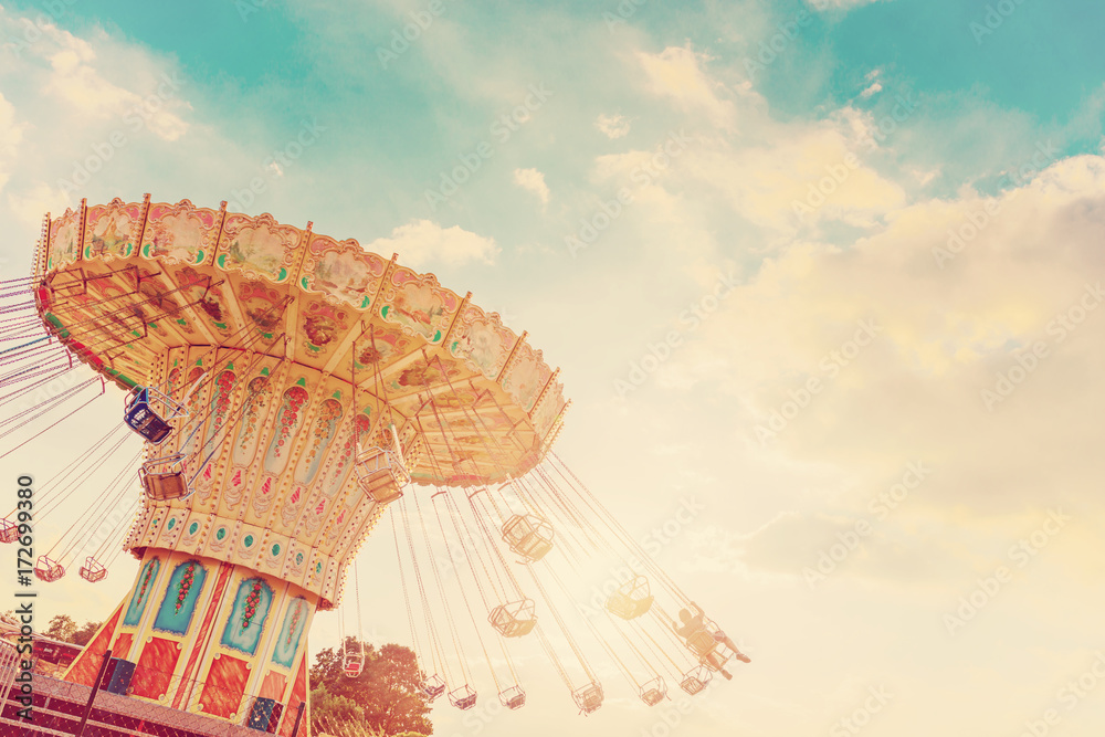 carousel ride spins fast in the air at sunset - vintage filter effects - a swinging carousel fair ride at dusk - obrazy, fototapety, plakaty 