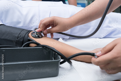 Nurse using sphygmomanometer and stethoscope to measuring blood pressure of patients with attention.