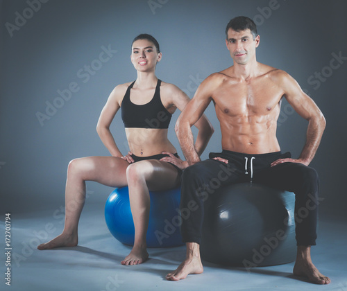 Two smiling people with fitness ball in the gym. Personal fitness instructor. Personal training. Gym workout.