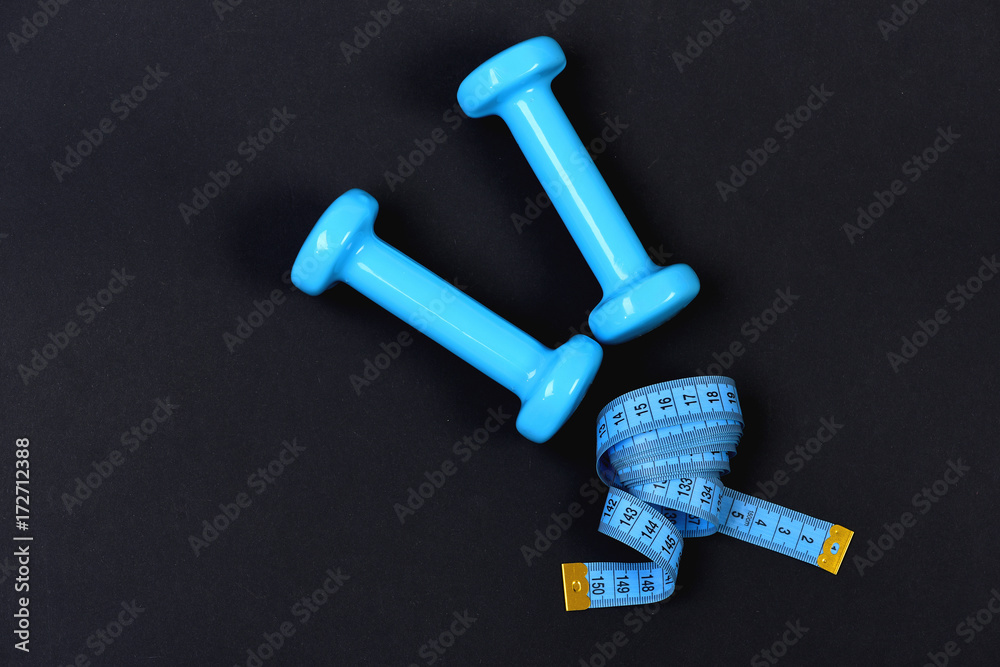 Dumbbells and measure tape in cyan blue color Dumbbells and measure tape in cyan blue color