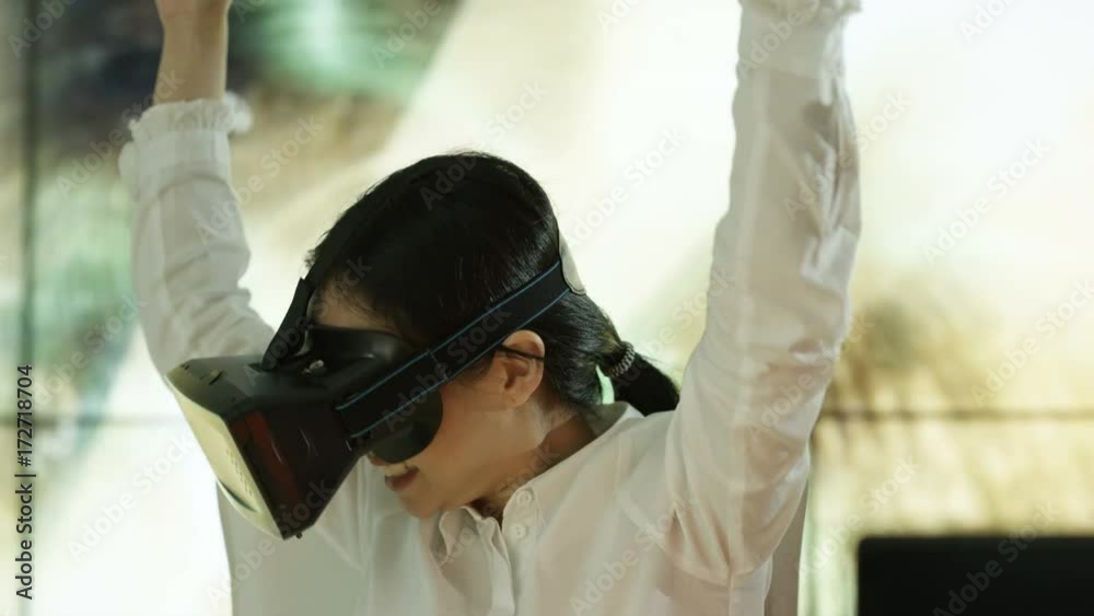 Businesswoman wearing virtual reality viewer at her desk with animated graphic of a data tunnel in background Businesswoman wearing virtual reality viewer at her desk with animated graphic of a data tunnel in background