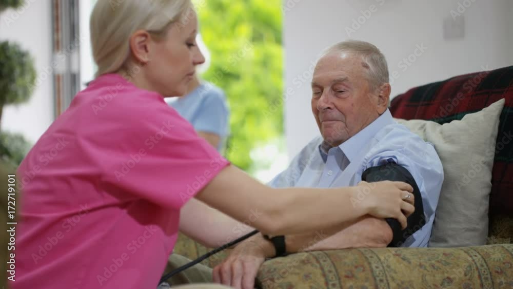 Young nurse checking elderly lady's blood pressure in nursing home. Young nurse checking elderly lady's blood pressure in nursing home.