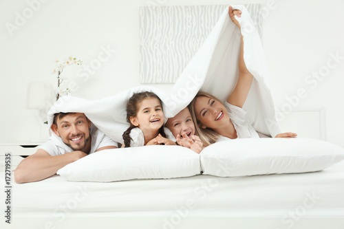 Family lying on bed in hotel room