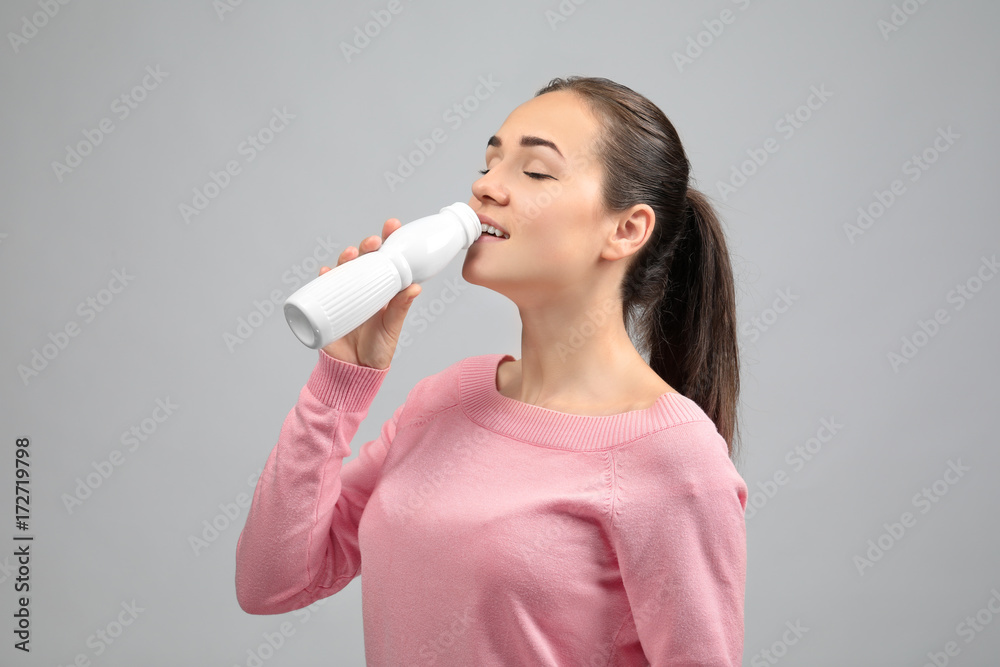 Young woman eating yogurt on light background Young woman eating yogurt on light background