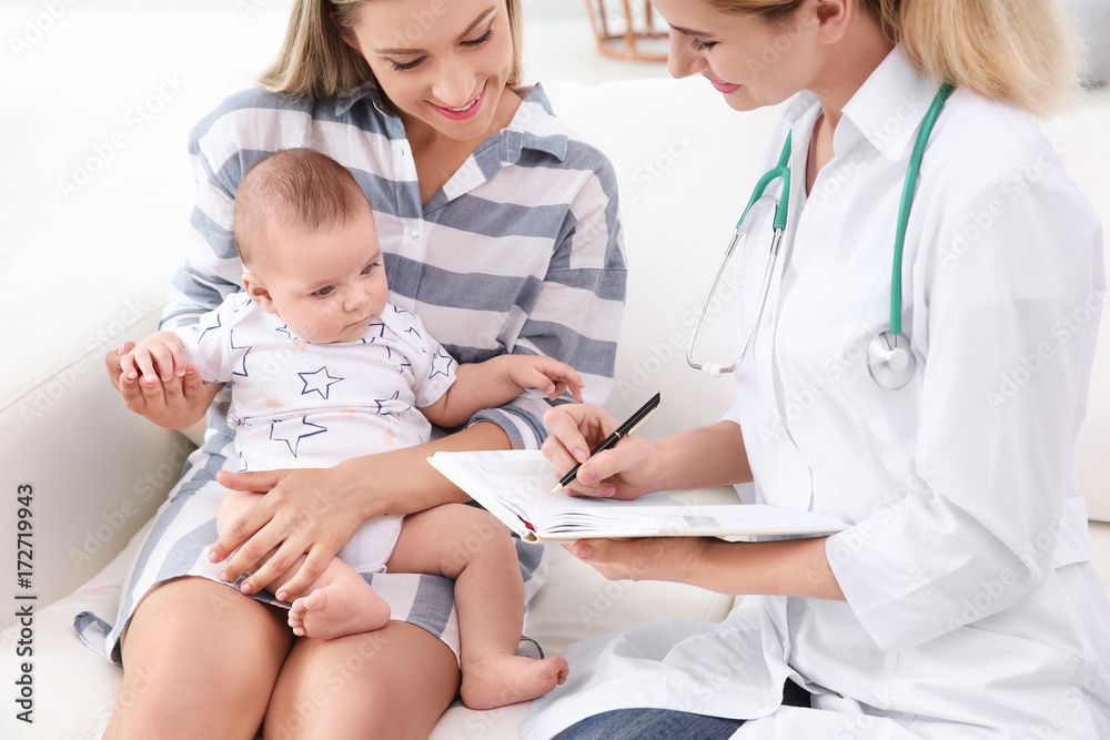 Doctor writing something in notebook and mother with baby at home Doctor writing something in notebook and mother with baby at home