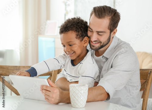 Happy father with adopted African-American boy using tablet computer at home © Africa Studio