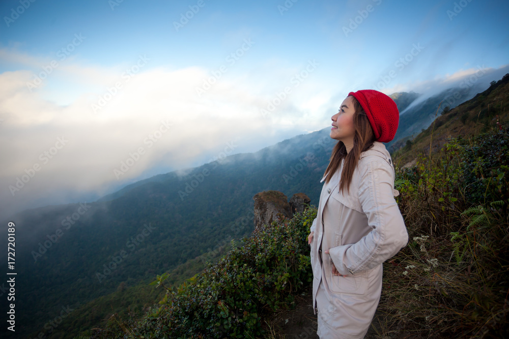 Young woman on a cliff overlooking the mountains