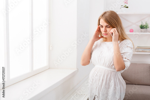 Worried pregnant woman talking on phone, copy space.