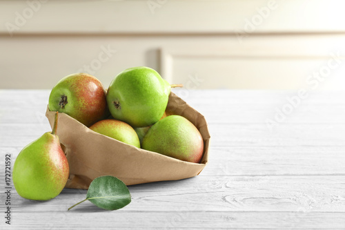 Paper bag and delicious ripe pears on table