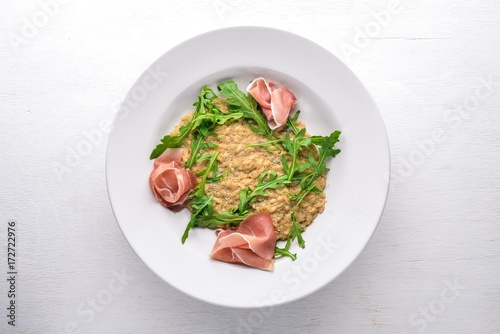 Risotto with diced meat and arugula. Top view. Free space.
