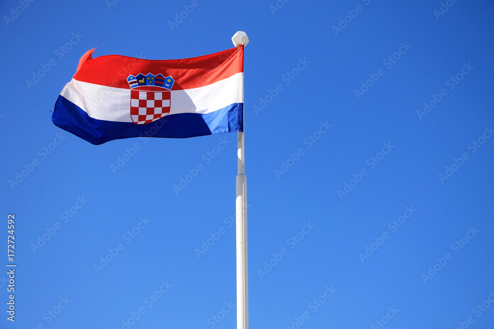 Flag of Croatia with flag pole waving in the wind with blue sky in background