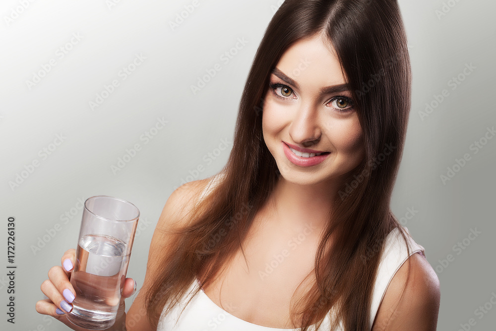 Drink water. Young girl drinking water from the glass. Daily water intake. Clean water. The concept of health and beauty. On a gray background. Drink water. Young girl drinking water from the glass. Daily water intake. Clean water. The concept of health and beauty. On a gray background.