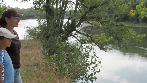 A woman with a child is looking at a river landscape. Mom and daughter are looking at the river. photo