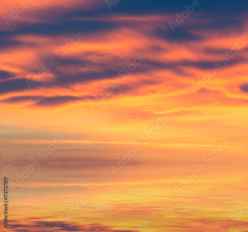 A beautiful "fiery" sunset in the sky with a glow from the sun over the sea. © Sviatoslav Khomiakov