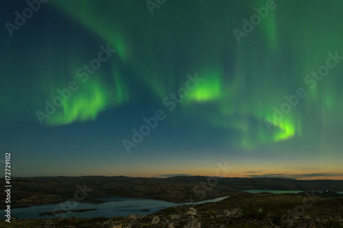 Autumn Aurora, the polar lights in the sky over the river,lake and hills at night . © Moroshka