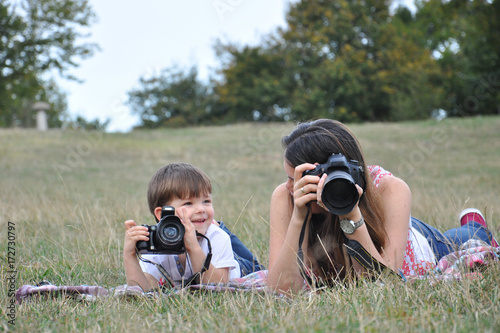 Mom and son make photos with digital camera. Woman photographer taking photo together with her son