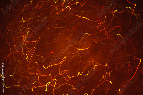 Abstract background of colorful crankles in motion on black. Bokeh of defocused curves, blurred neon orange leds, similar to gas discharge plasma ball, tesla sphere photo