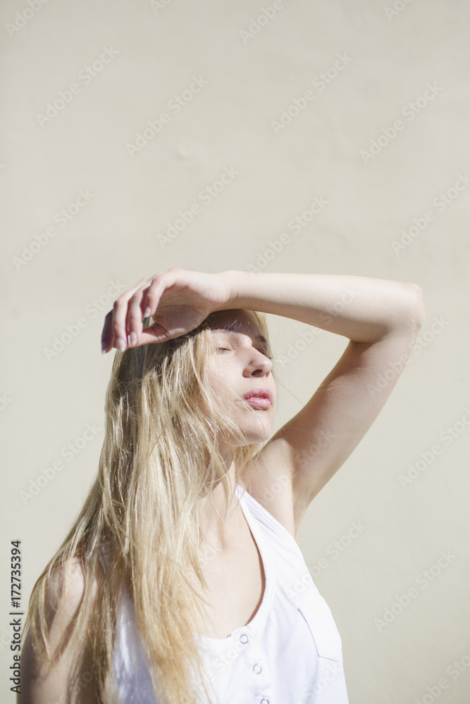 Blonde girl with arm raised for sun protection Blonde girl with arm raised for sun protection