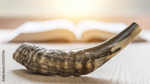 Yom Kippur and Rosh Hashanah (Hashana)  (jewish New Year holiday) concept with Ram shofar (horn) with religious holy prayer book on table