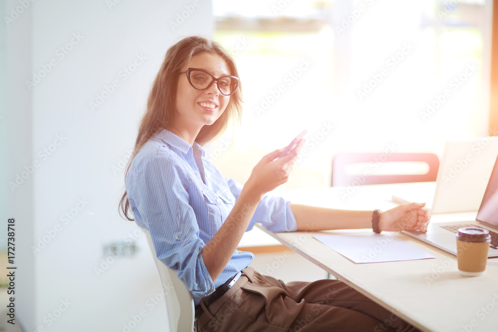 Beautiful young business woman sitting at office desk and talking on cell phone. Business woman Beautiful young business woman sitting at office desk and talking on cell phone. Business woman