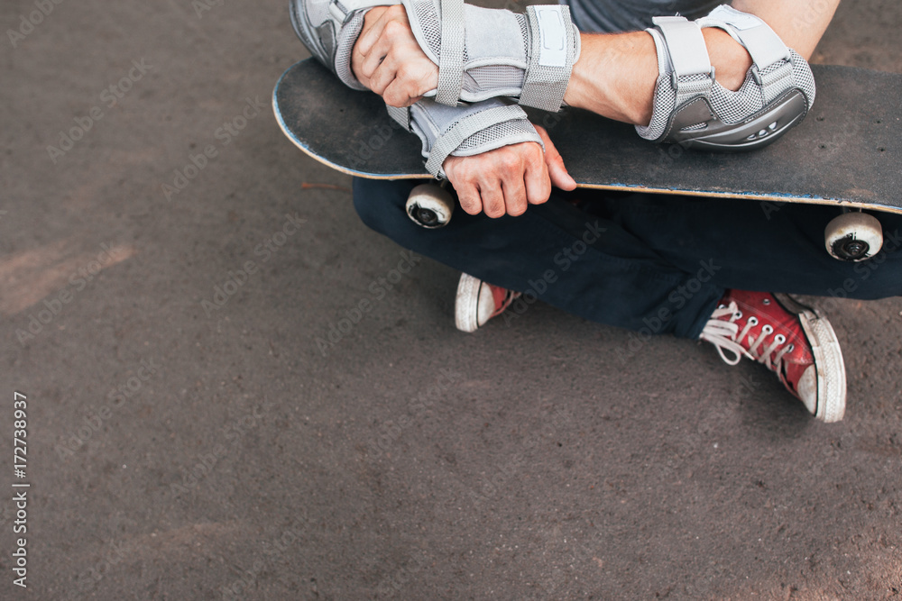 Professional skater sitting with skate, ready to next competition. Extreme sport challenge and training, skateboarder modern lifestyle and culture of young people background with free space Professional skater sitting with skate, ready to next competition. Extreme sport challenge and training, skateboarder modern lifestyle and culture of young people background with free space