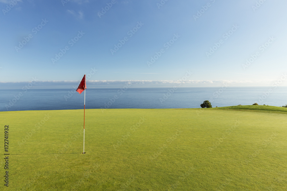 Golf flag on grassy field against blue sky