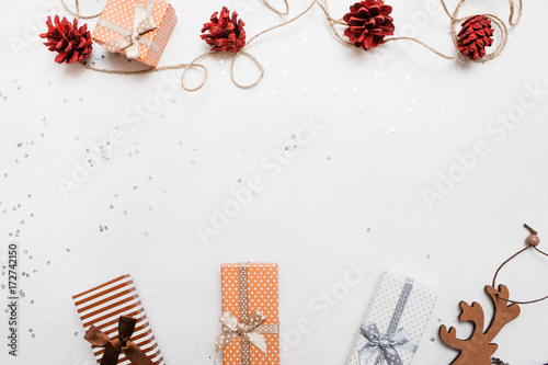 Festive background of Christmas holiday. Gift boxes on white background with silver star tinsels and strobila decoration above, top view with copy space. Celebrations, New Year, festival concept photo