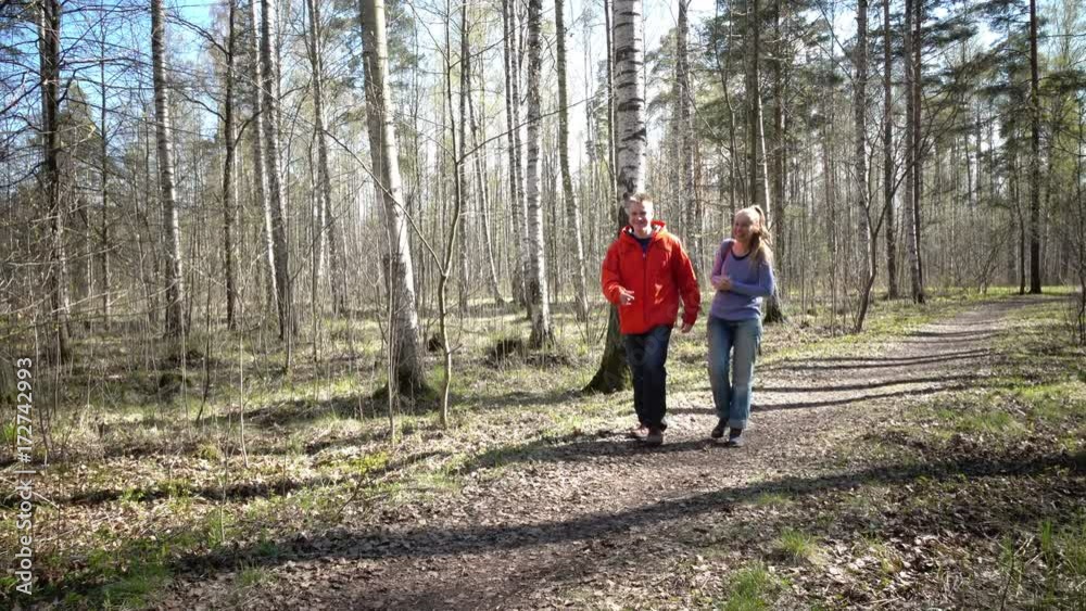Loving young couple the man and the woman go on a path of the spring park talking with each other Loving young couple the man and the woman go on a path of the spring park talking with each other