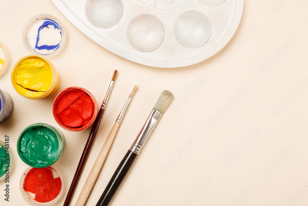 Paintbrushes, open paint jars and palette on a table, top view, copy space Paintbrushes, open paint jars and palette on a table, top view, copy space