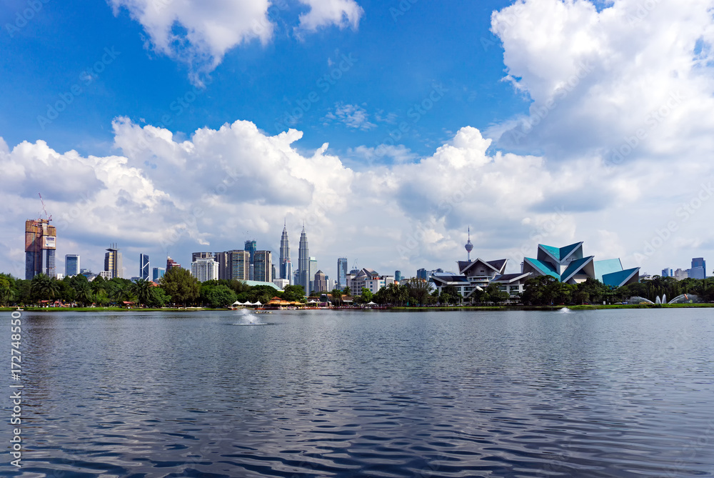 Sunny with blue sky and clouds over Kuala Lumpur Skyline seen from Taman Tasik Titiwangsa in Malaysia.