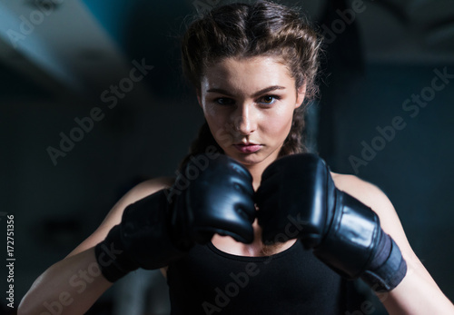 Young fighter boxer girl wearing boxing gloves before  training. She is looking at camera © Igor Kardasov