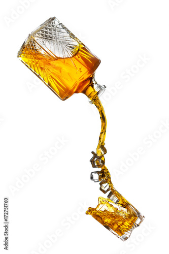 Bottle pouring splash of liquor and ice in a glass