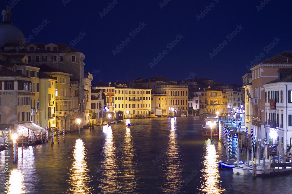 Panoramic night view of Canal Grande from above. Lights of restaurants and shops reflected on the water.
