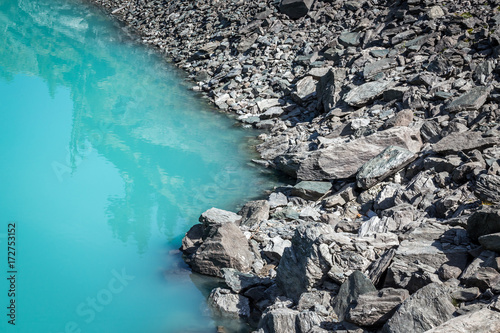 le bord d'un lac bleu avec des rochers gris