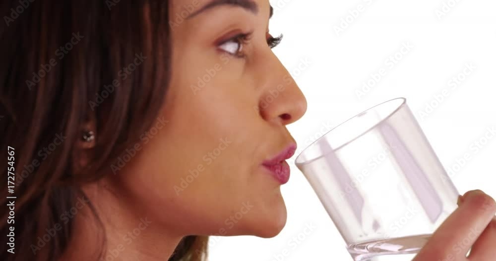 Close up of healthy Latina female taking pill then drinking water on white background. Portrait of young woman taking daily supplement in studio. 4k Close up of healthy Latina female taking pill then drinking water on white background. Portrait of young woman taking daily supplement in studio. 4k