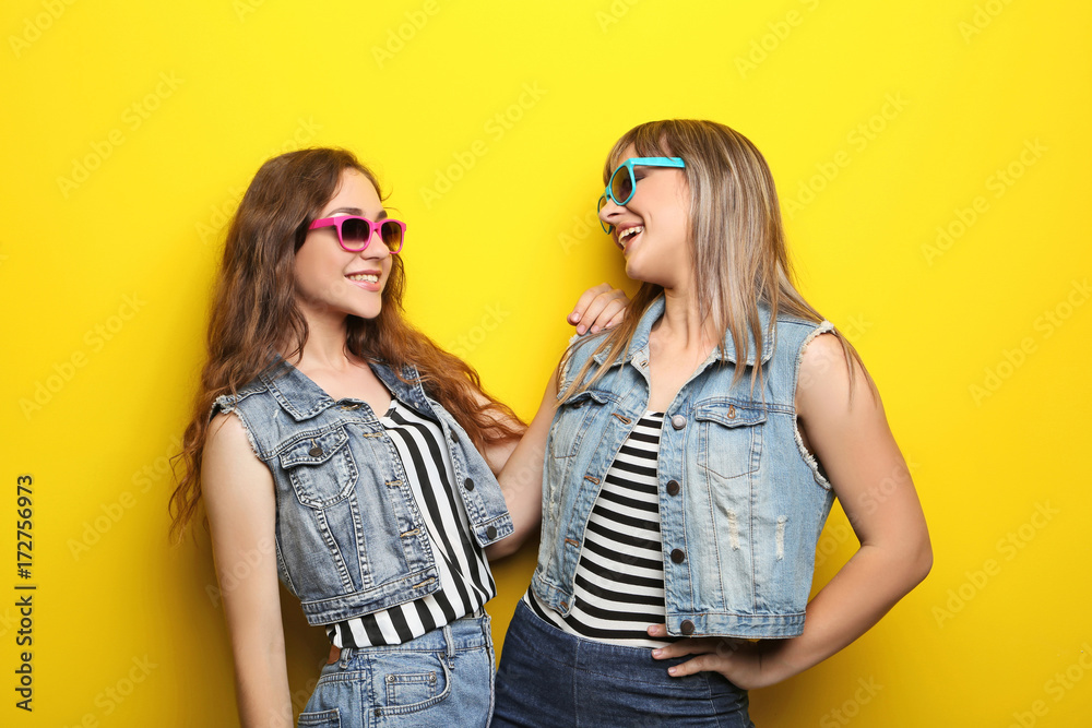 Portrait of two young woman with sunglasses on yellow background Portrait of two young woman with sunglasses on yellow background