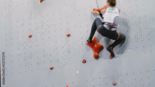 Girl quickly climbs up the wall in the room for climbing photo