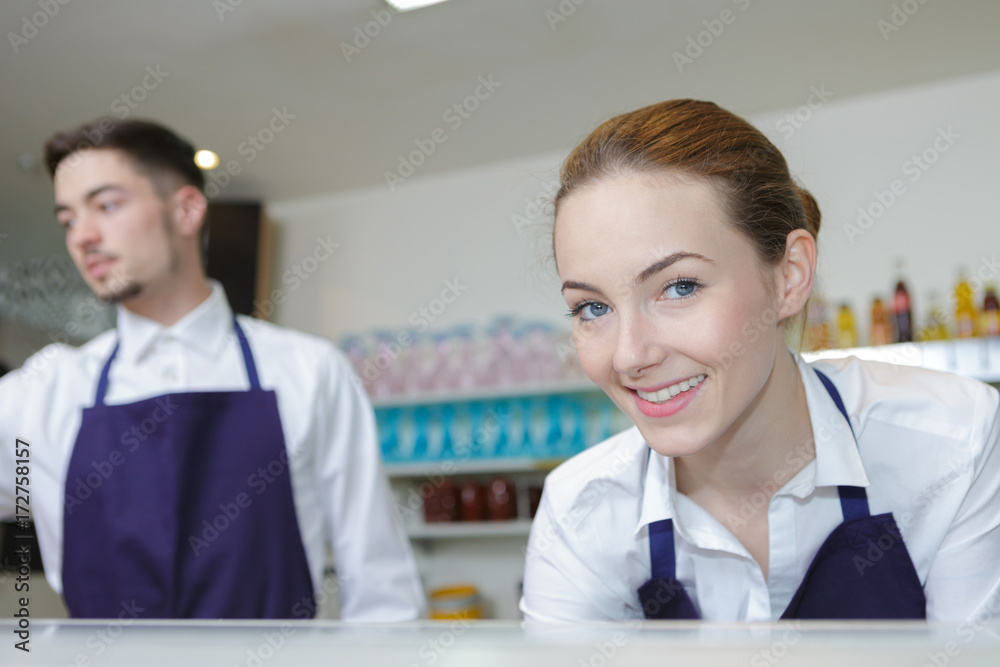 Young man and woman behind food counter Young man and woman behind food counter